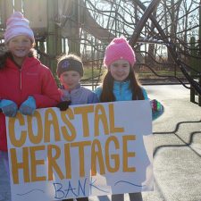 Kids holding a Coastal Heritage Bank sign